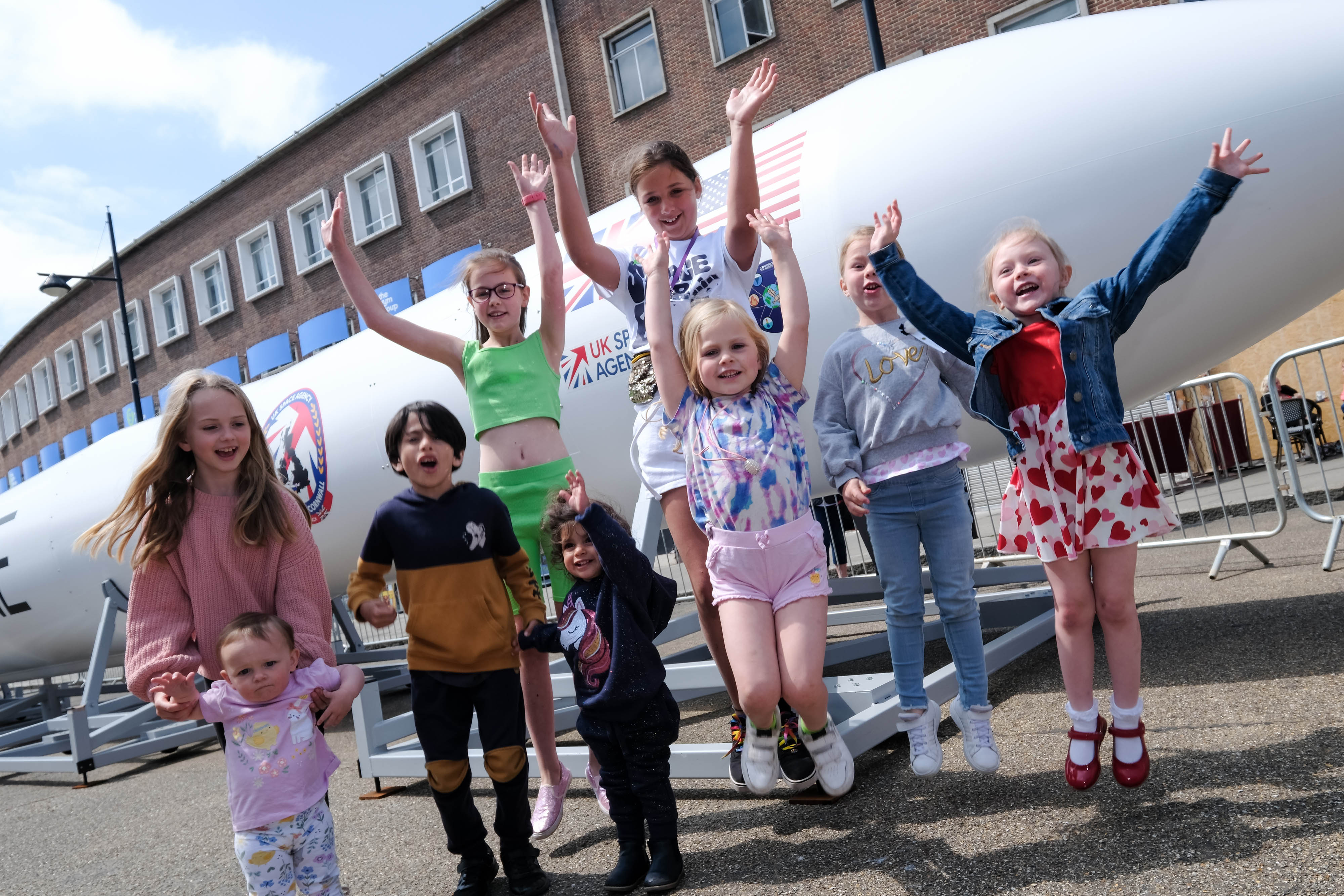 Children celebrating in front of replica rocket.