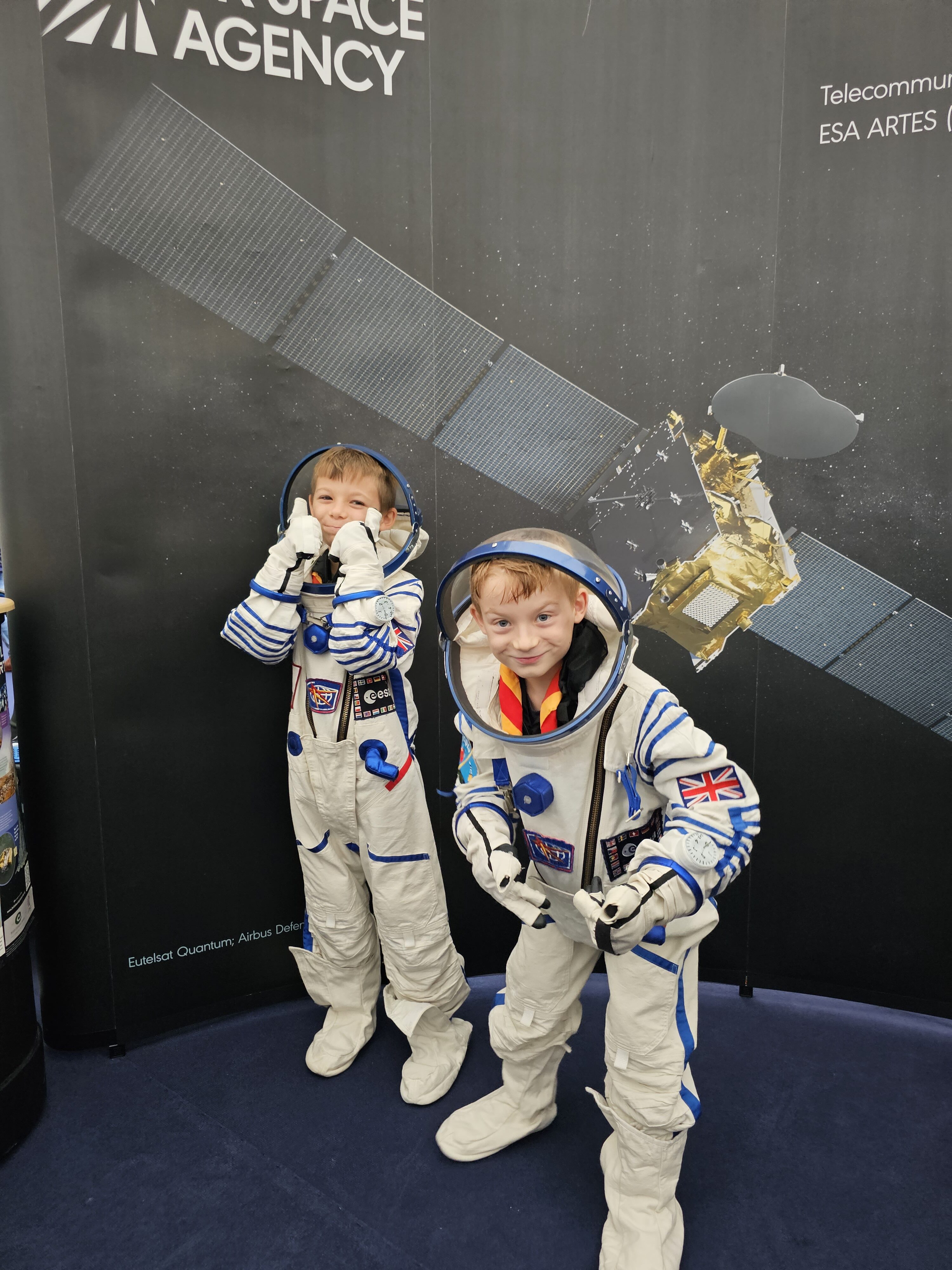 Two children in astronaut suits in front of UK Space Agency banner