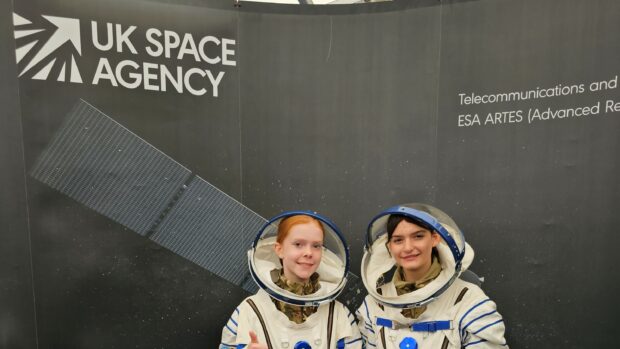 Two young people in spacesuits in from of UK Space Agency banner