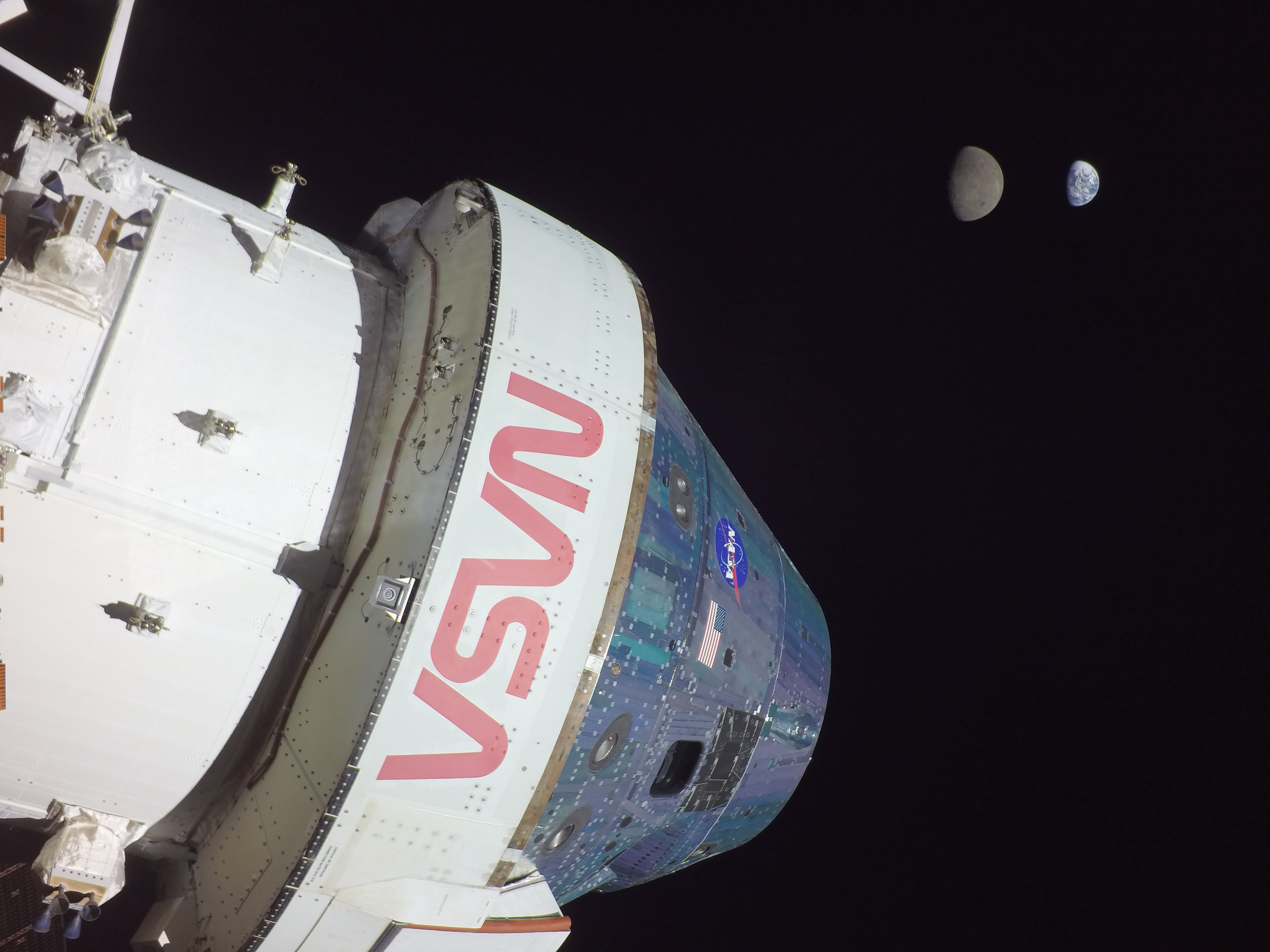 The Orion capsule with the Earth and the Moon in the background, seen from a camera mounted on one of the spacecraft's solar arrays.